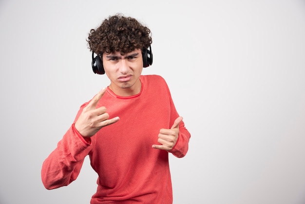 Curly young man with headphones making signs.