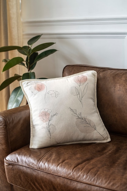 Free Photo cushion with minimal floral line art on a leather couch