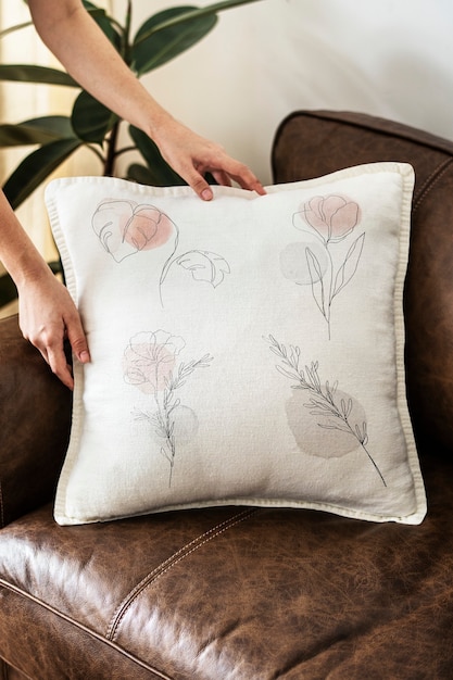 Free Photo cushion with minimal floral line art on a leather couch