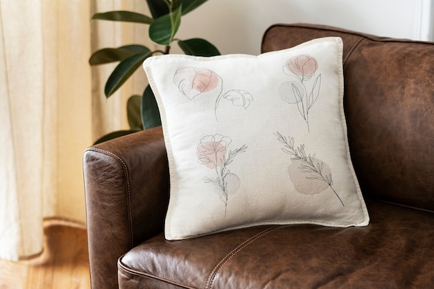 Free Photo cushion with minimal floral line art on a leather couch