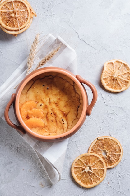 Custard puddings in cooking pot on concrete backdrop