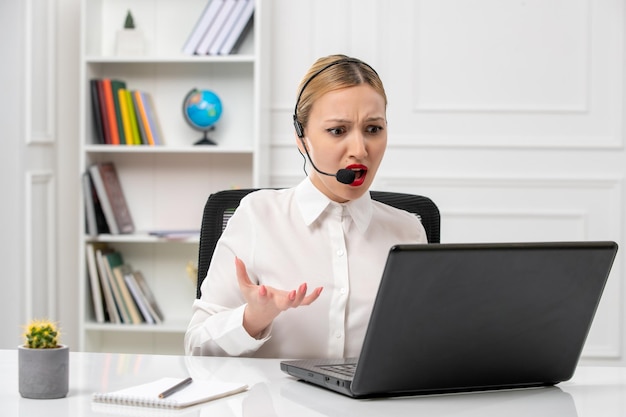 Free photo customer service cute beautiful girl in white shirt with computer and headset annoyed on a call