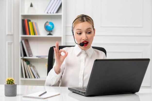 Customer service cute beautiful girl in white shirt with computer and headset showing ok gesture