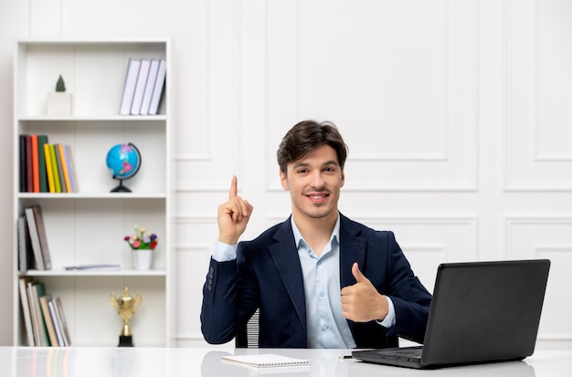 Customer service the cute brunette guy in the suit with laptop happy pointing up