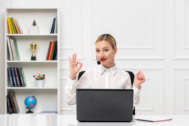 Customer service cute woman in white shirt with headset and computer showing ok gesture