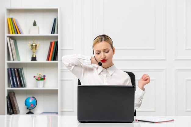 Customer service cute woman in white shirt with headset and computer tired touching neck