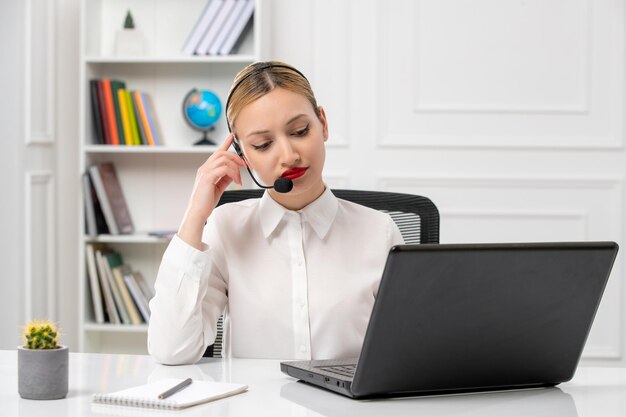 Customer service pretty blonde girl in white shirt and laptop and headset tired with hands on head