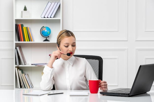 Customer service pretty blonde girl in white shirt with laptop and headset talking on a microphone