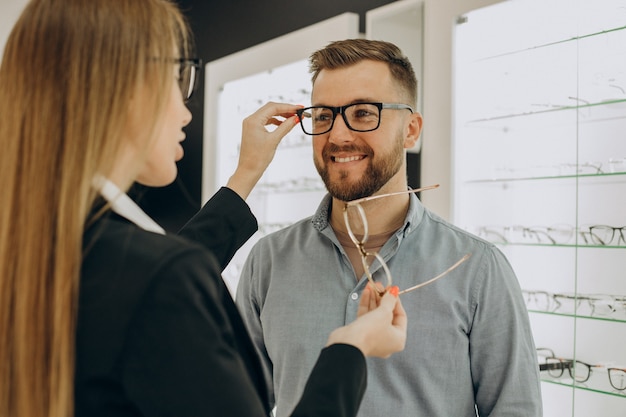 Free photo customer shoosing spectacles at optic store with the help of sales person