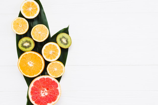 Cut of fresh exotic fruits on banana leafs on white background