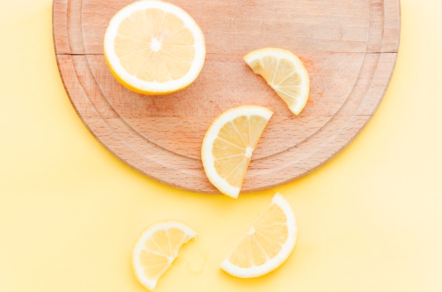 Free photo cut lemon on wooden plate