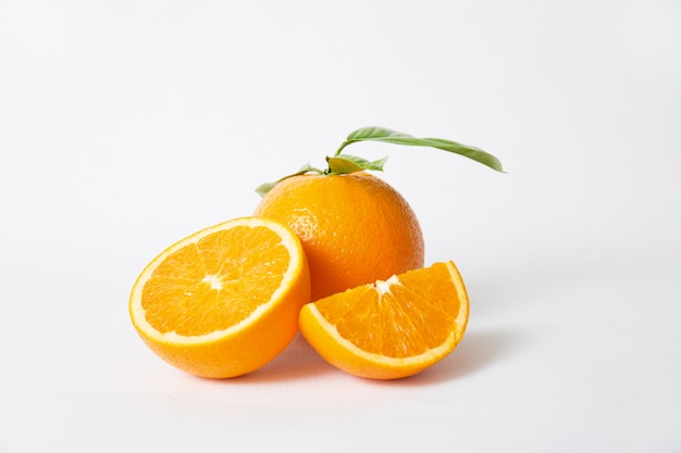 Free photo cut orange parts and whole fruit with green leaves