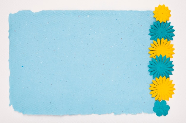 Free Photo cut out flowers border on blue paper over white backdrop