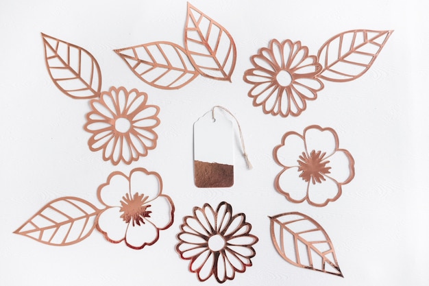 Free photo cut out golden flowers and leaves with tag in the center on white background