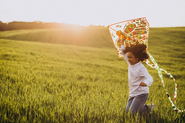 Cute african baby girl at the field on the sunset playing with kite