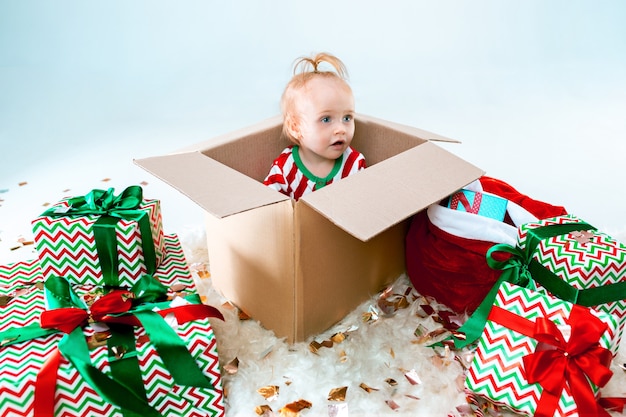 Cute baby girl sitting in box over Christmas background. Holiday, celebration, kid concept