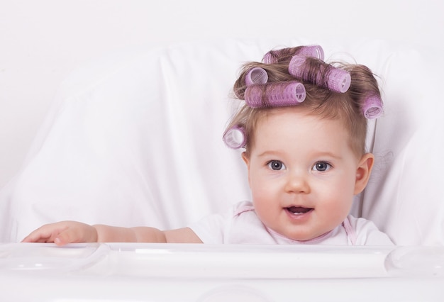 Free photo cute baby girl with plastic hair rollers