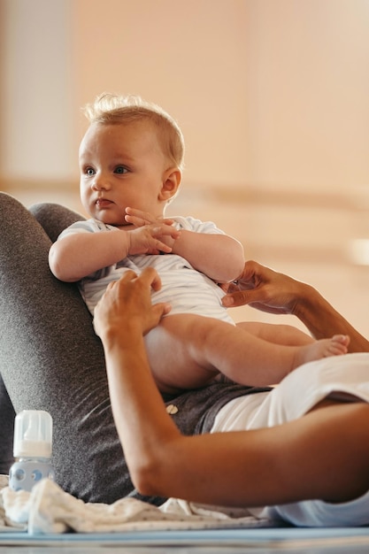 Free photo cute baby and his unrecognizable mother during workout in a health club