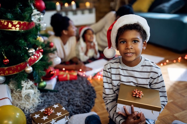 Cute black boy with gift box on Christmas day at home