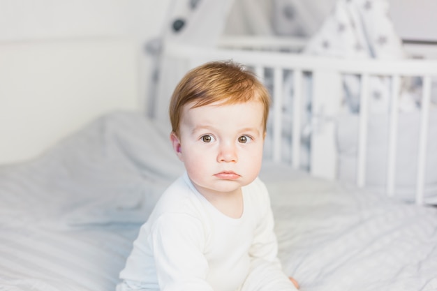 Cute blonde baby in white bed