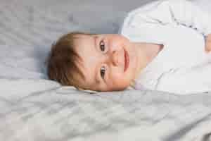 Free photo cute blonde baby in white bed