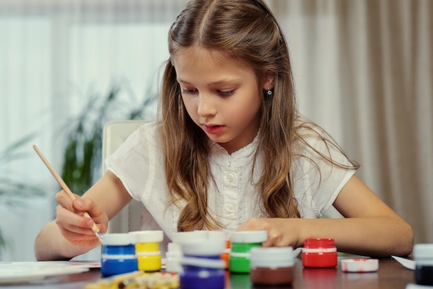 Free Photo cute blonde girl painting with acrylic paint in art studio class.