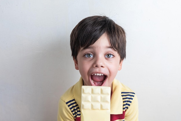 Free photo cute boy eating white chocolate