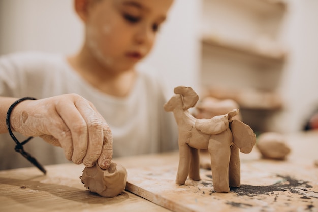 Cute boy forming toys from clay