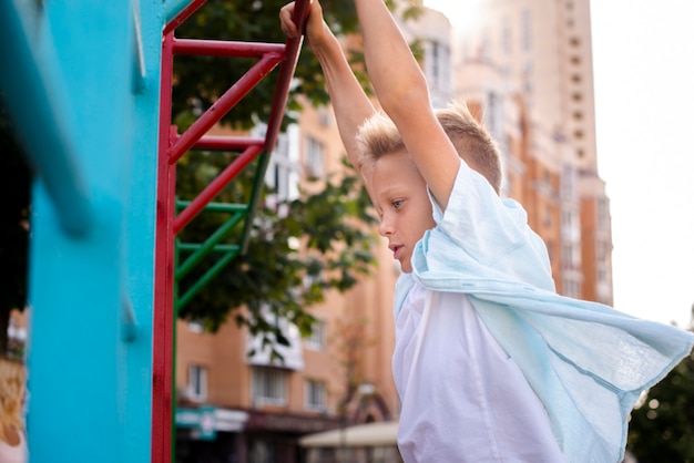 Cute boy hanging on a bar with his hands