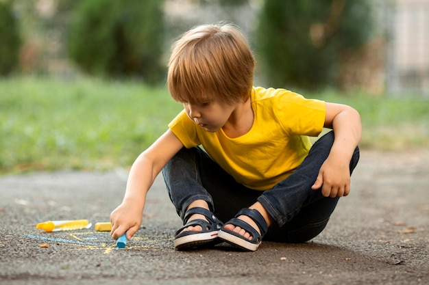 Free photo cute boy in park drawing with chalk