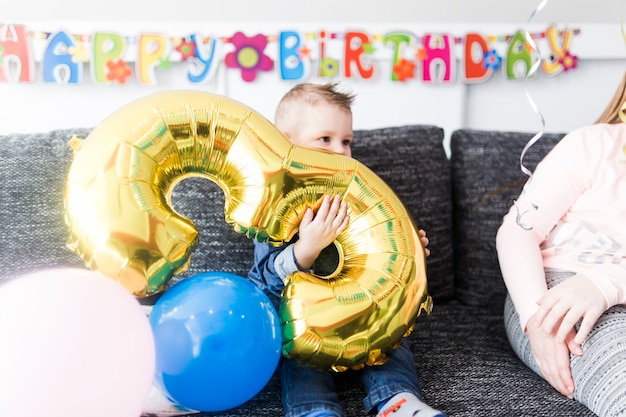 Cute boy with balloon on couch