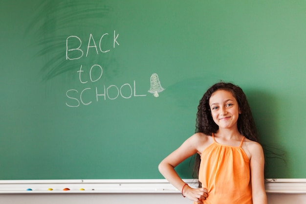 Free photo cute brunette pupil girl at blackboard