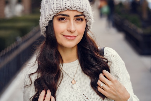 Cute brunette in a white sweater in a city