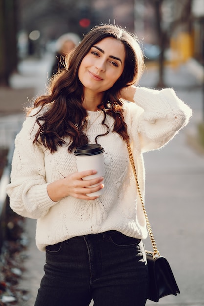 Cute brunette in a white sweater in a city