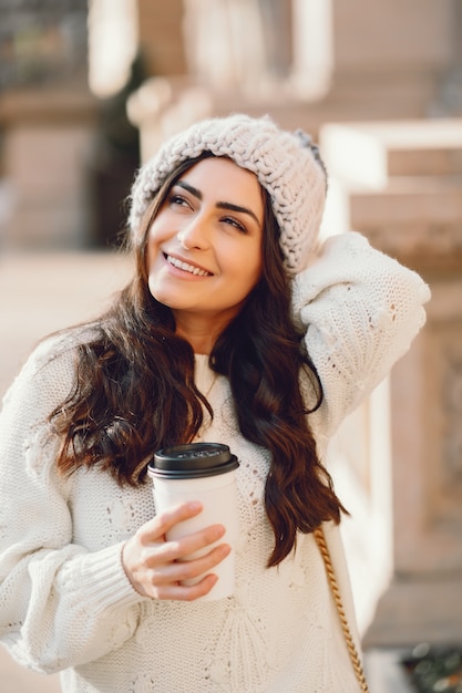 Cute brunette in a white sweater in a city