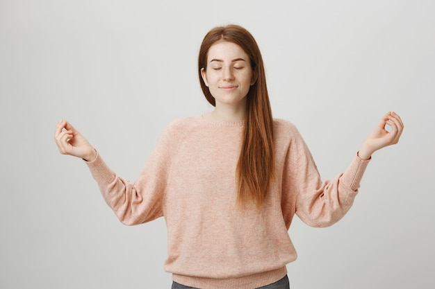 Free photo cute calm redhead girl meditating, raise hands in zen gesture