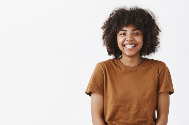 Free Photo cute carefree friendly-looking african american teenage girl with afro hairstyle smiling broadly with shy and happy expression meeting new classmates