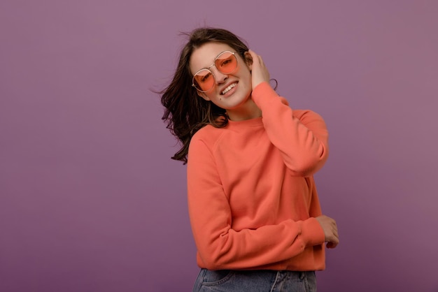 Free photo cute caucasian young brunette girl in glasses and blouse looks at camera on purple background leisure lifestyle and beauty concept