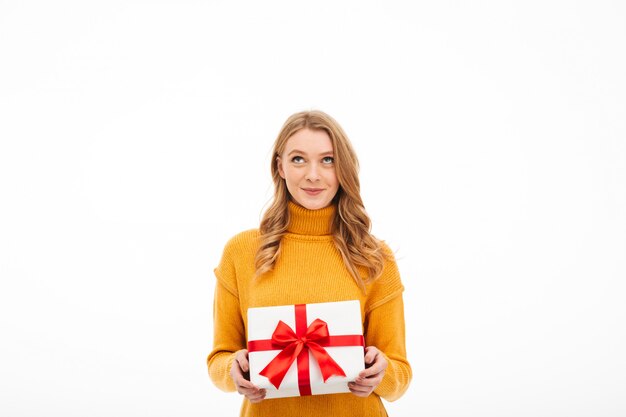 Cute cheerful young woman holding surprise gift box.