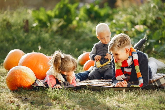 Cute childresn sitting on a garden near many pumpkins