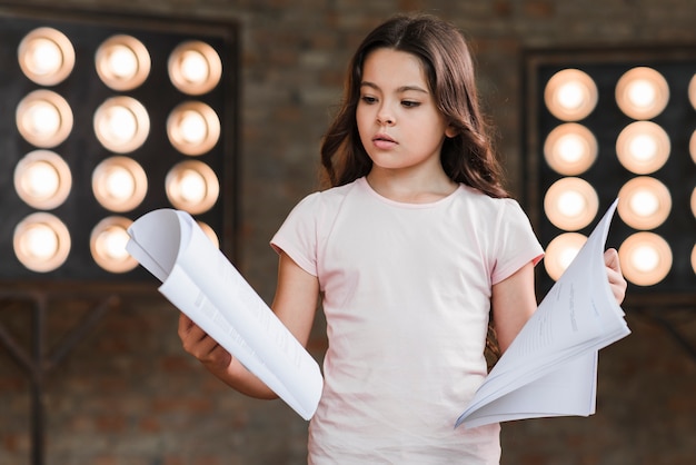 Free photo cute confused girl holding scripts in hands