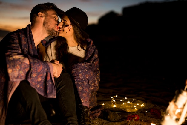 Free photo cute couple in blanket kissing on sea shore