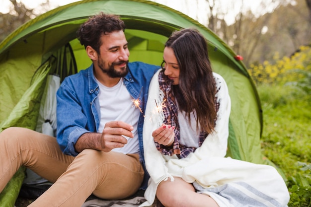 Free photo cute couple burning sparklers in nature