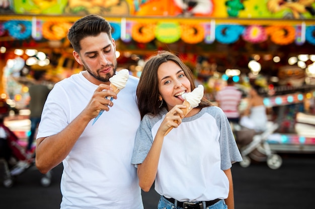 Cute couple eating ice creams at fair