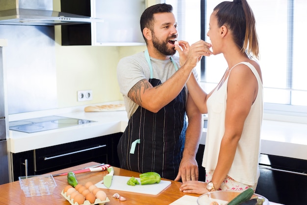 Cute couple feeding each other in kitchen