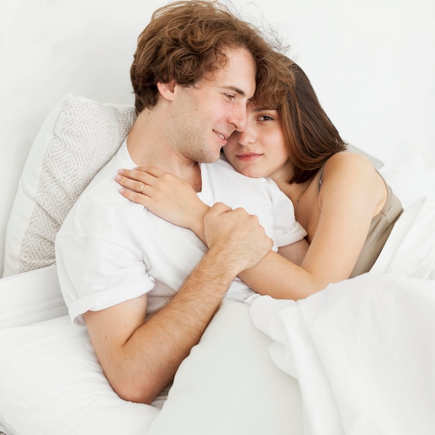 Cute couple hugging in bed medium shot