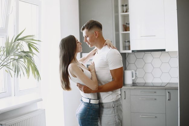 Cute couple in a kitchen. Lady in a white t-shirt. Pair at home