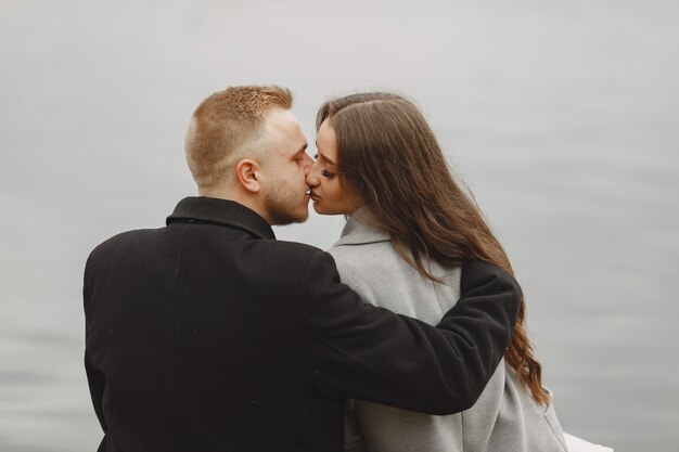 Cute couple in a park. Lady in a gray coat. People on the pier.