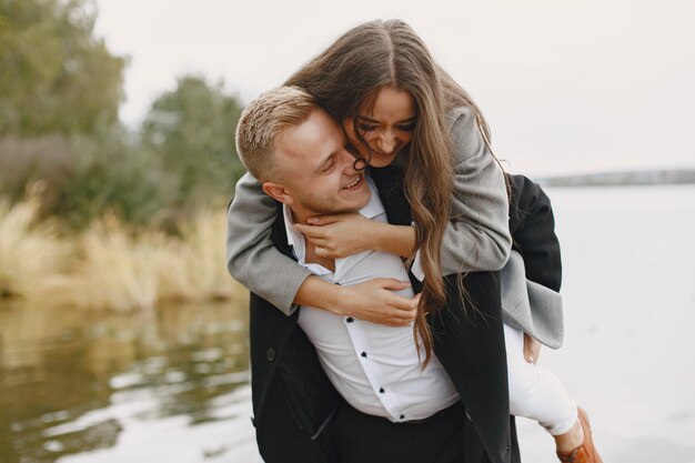 Cute couple in a park. Lady in a gray coat. People on the pier.