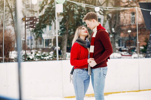 Cute couple in a red sweaters having fun in a ice arena